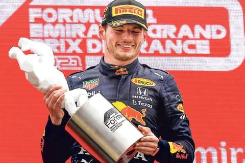 Max Verstappen celebrates on the podium with the trophy