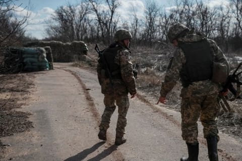 Ukrainian service members walk near the front line near the city of Novoluhanske (Reuters)