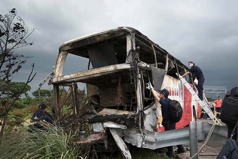 Police work around the wreckage of a bus that crashed en route to Taoyuan airport
