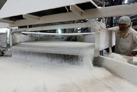 A worker checks the flow of sugar inside a sugar factory