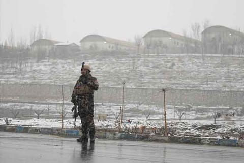 An Afghan security force member stands guard near the site of an attack on military academy in Kabul