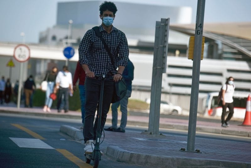 A Dubai office goer rides an e-scooter.