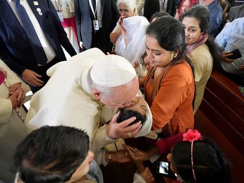 Pope Francis kisses a child during a visit to the St Joseph's Cathedral in Abu Dhabi. 