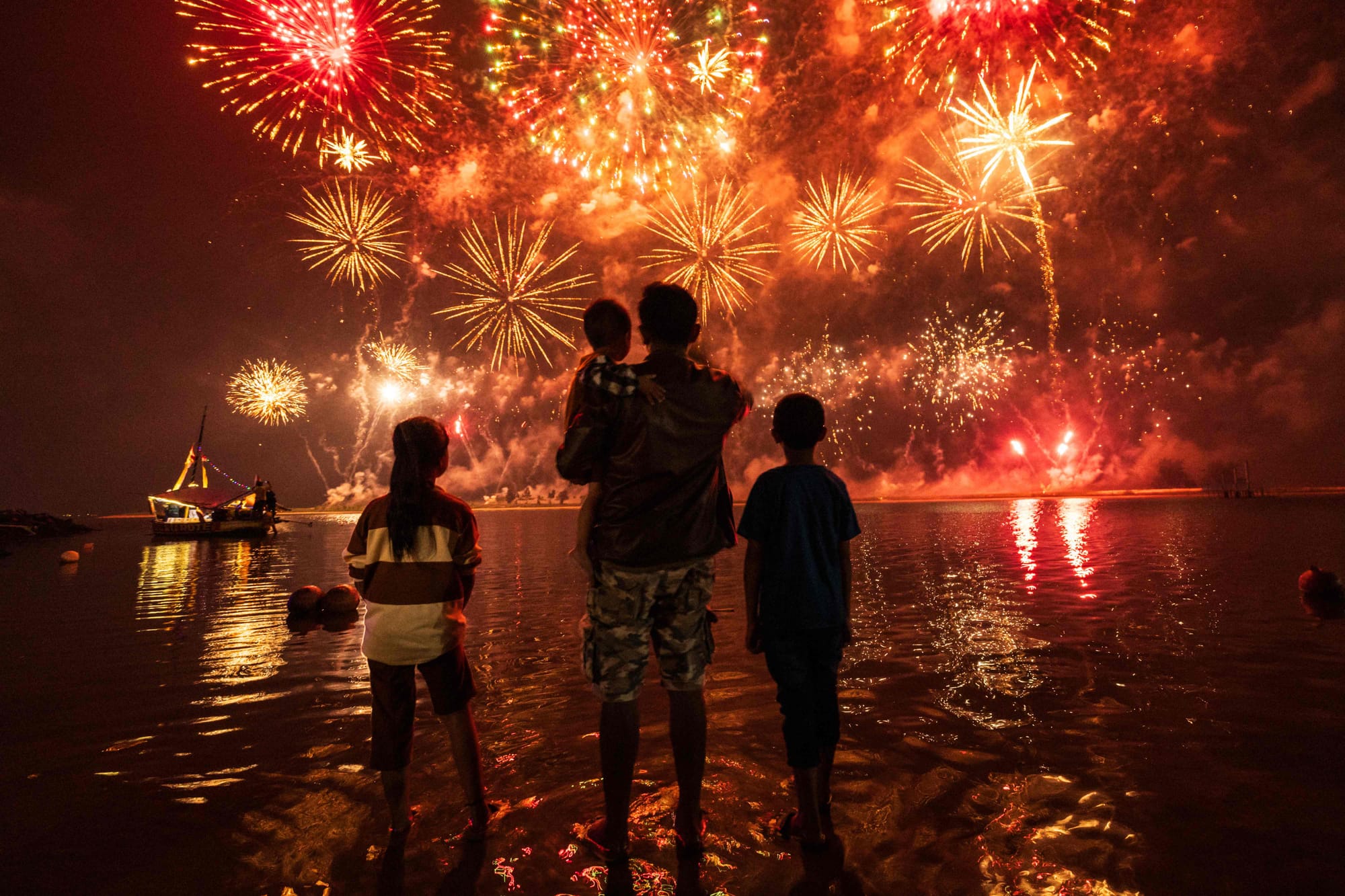 Local residents look at fireworks as they celebrate the New Year at Ancol Beach in Jakarta on January 1, 2025.