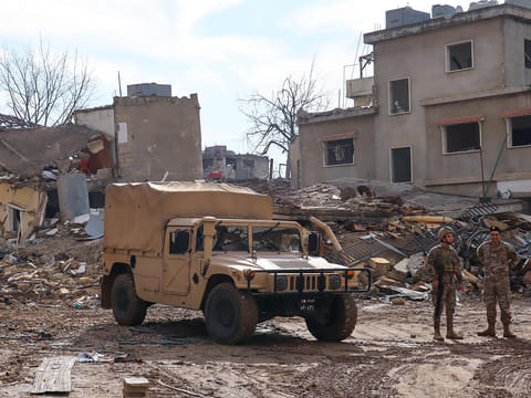 Lebanese soldiers stand next to damaged buildings in the southern Lebanese village of Khiam on December 23, 2024, after the withdrawal of Israeli forces from the area under a ceasefire deal with Hezbollah.  