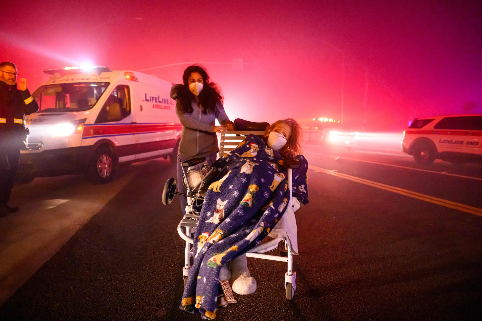 Elderly patients are quickly evacuated into emergency vehicles as embers and flames approach during the Eaton fire in Pasadena, California.