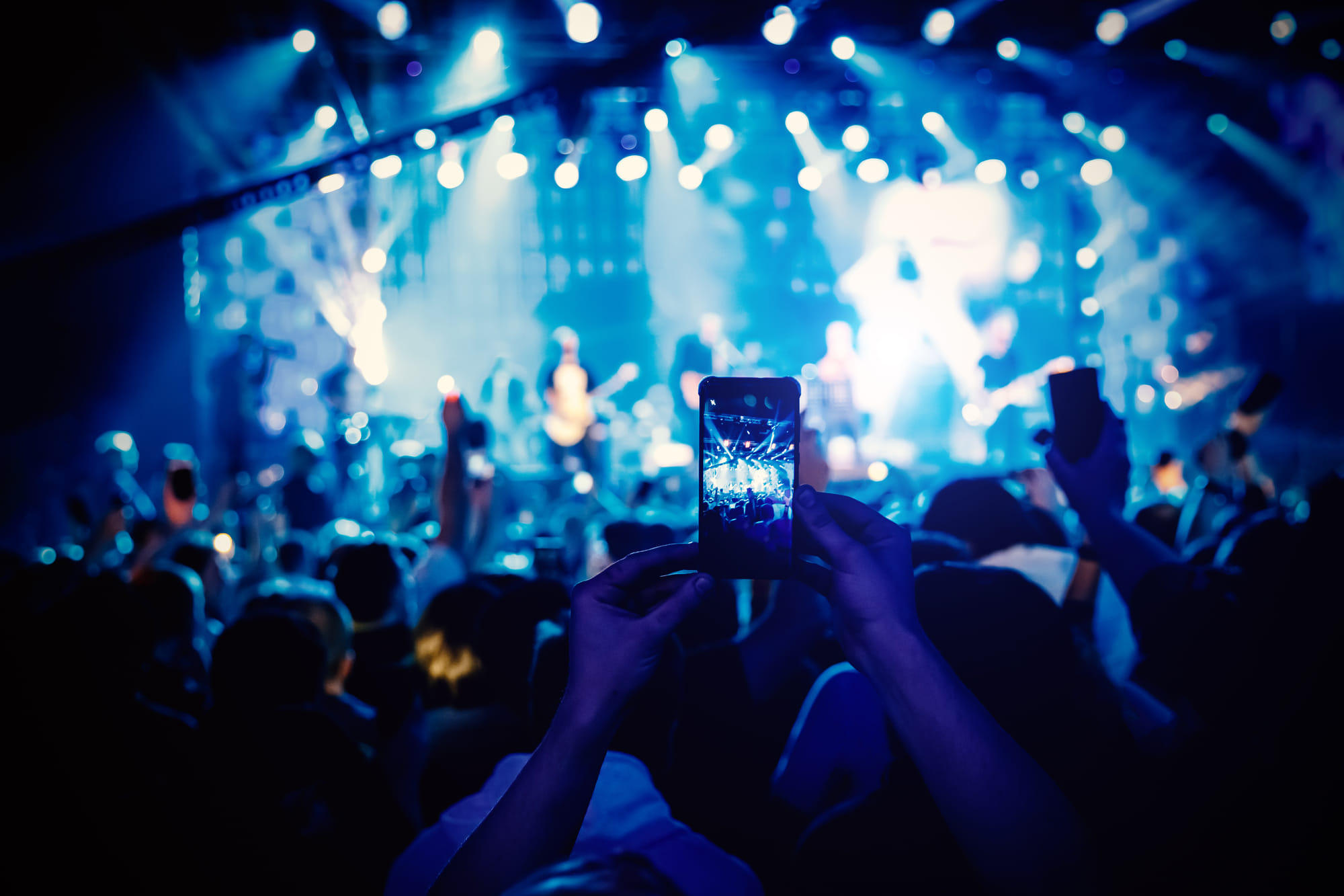 Man takes a picture of the show at the concert hall using a smartphone. Pics for illustrative purposes alone