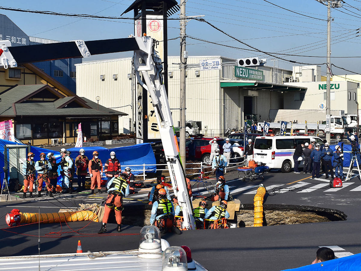 Firefighters work to rescue a truck driver after his vehicle was swallowed up by a sinkhole at a prefectural road intersection, in the city of Yashio, Saitama Prefecture on January 28, 2025.