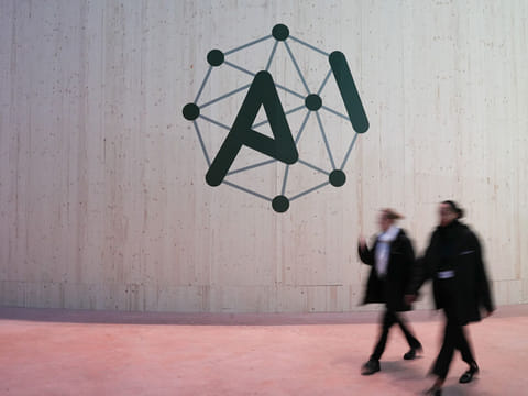 Attendees walk pass an AI Action Summit logo sign at the Grand Palais in Paris, France, on Monday, Feb. 10, 2025.  