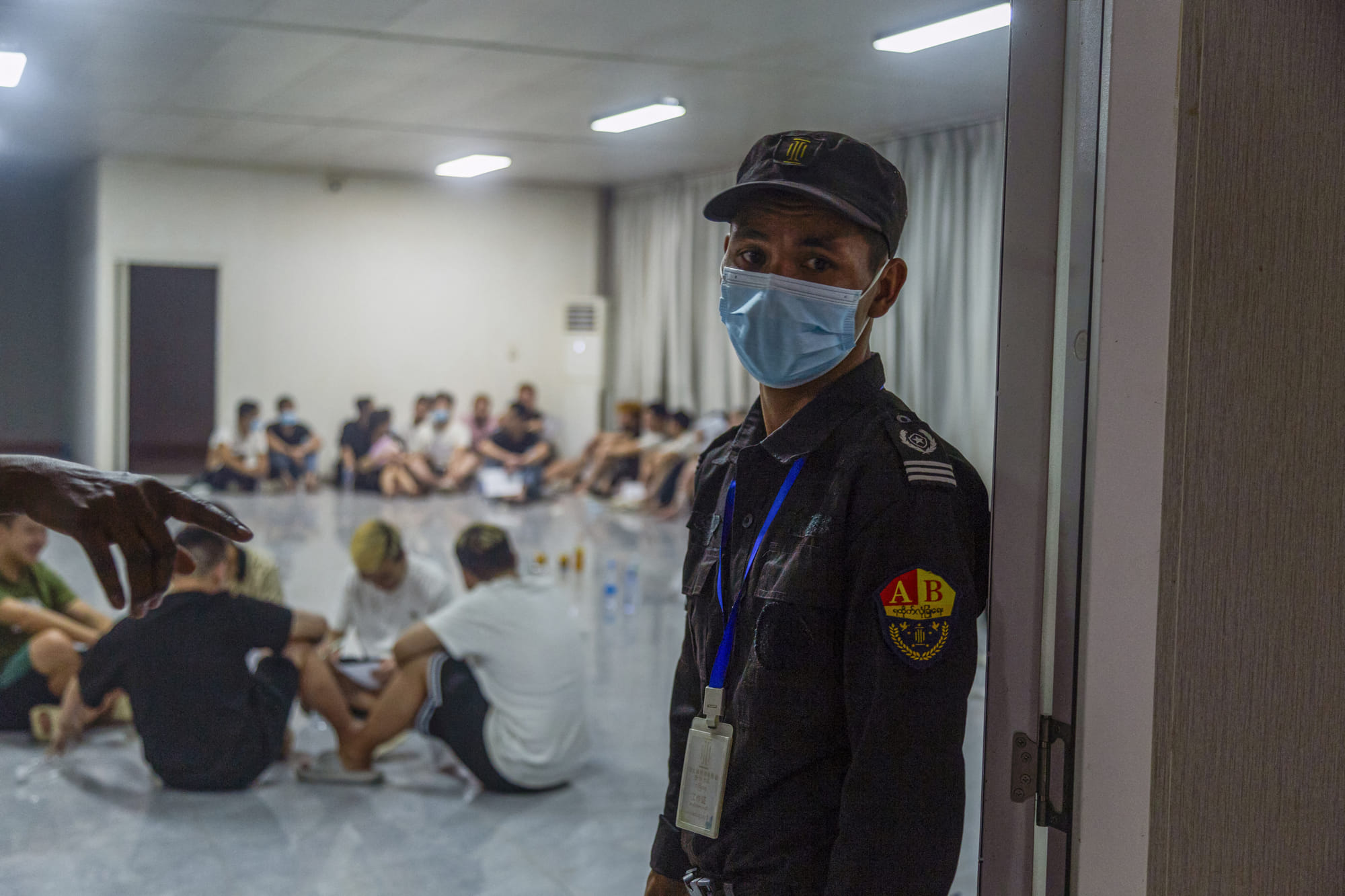 A security guard stands guard next to a room full of alleged scam centre workers and victims during a crackdown operation by the Karen Border Guard Force (BGF) on illicit activity in Shwe Kokko in Myanmar's eastern Myawaddy township on February 14, 2025.