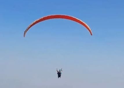 A viral video shows Samarth soaring with his college bag, fully geared in paragliding equipment.