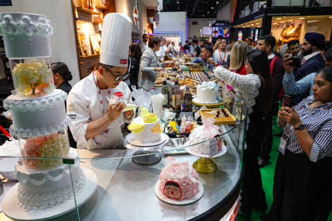 Visitors watch as a chef demonstrate cake decorating skills on the opening day of Gulffood 2025, annual F&B event at Dubai World Trade Centre.