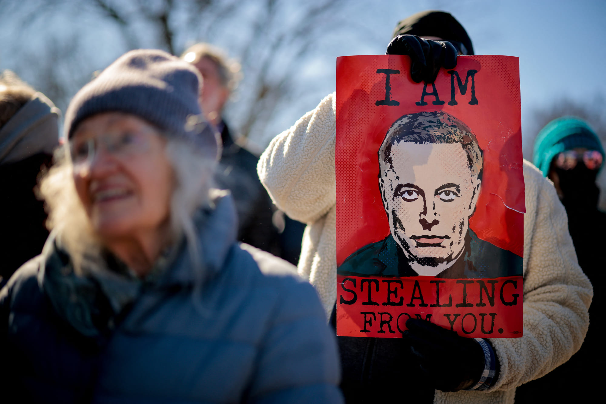 A sign depicting Tesla and SpaceX CEO Elon Musk is visible as protesters rally against the Trump administration during "Not My President's Day" protests at the Capitol Reflecting Pool on February 17, 2025 in Washington, DC.