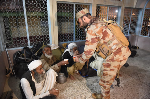 A soldier hands out tea to freed train passengers gathered at the Mach railway station, which has been turned into a makeshift hospital, after Pakistani security forces freed them following a security operation,