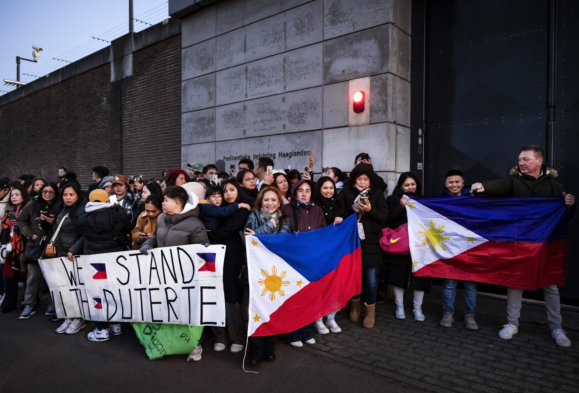 Protesters holding Filipino flags and a banner in support of former Philippine President Rodrigo Duterte gather outside the The Hague Penitentiary Institution prison.