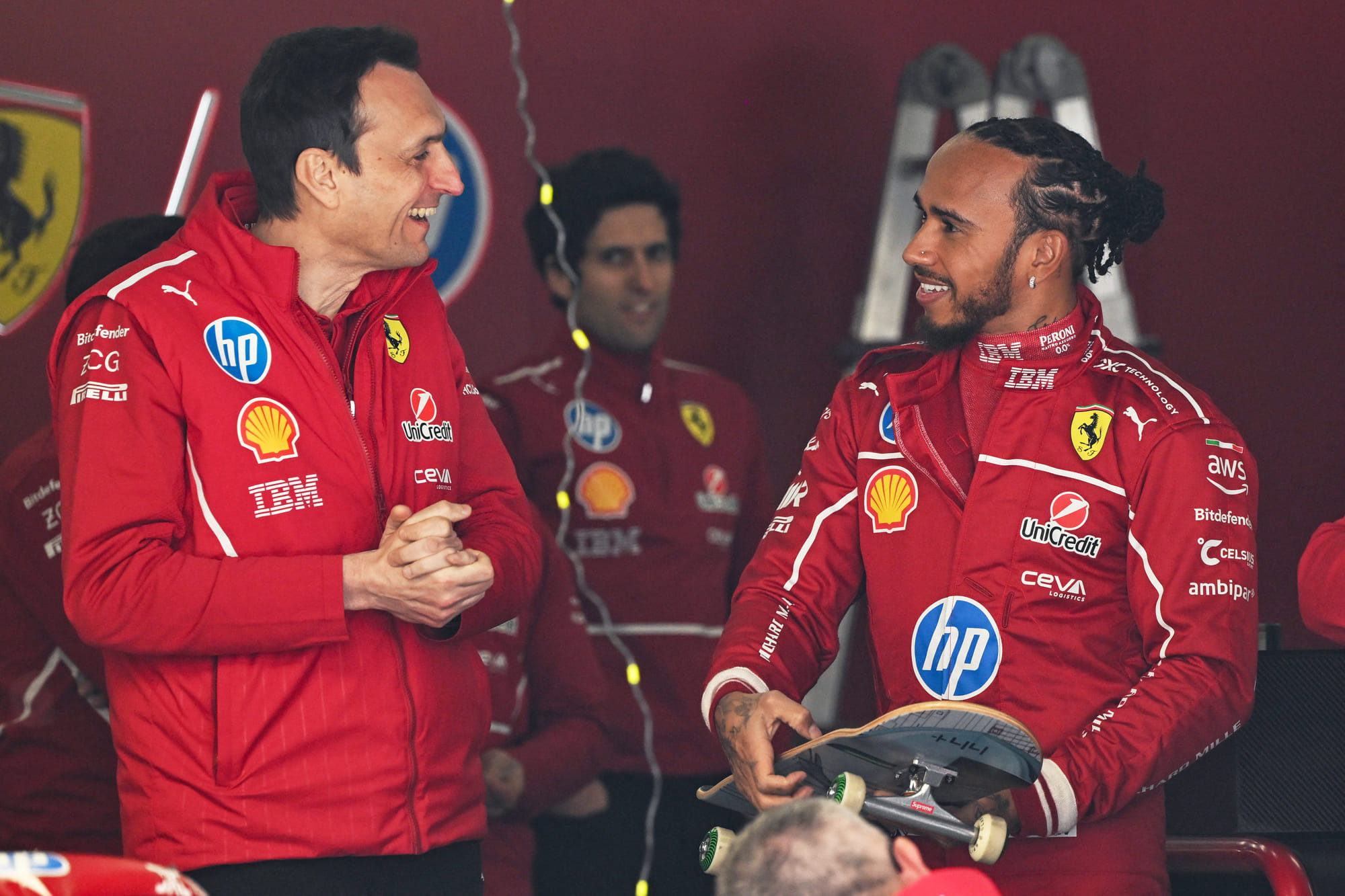 Ferrari's British driver Lewis Hamilton chats with team members while holding a skateboard in the Ferrari pit garage ahead of the Formula One Chinese Grand Prix in Shanghai on March 20.