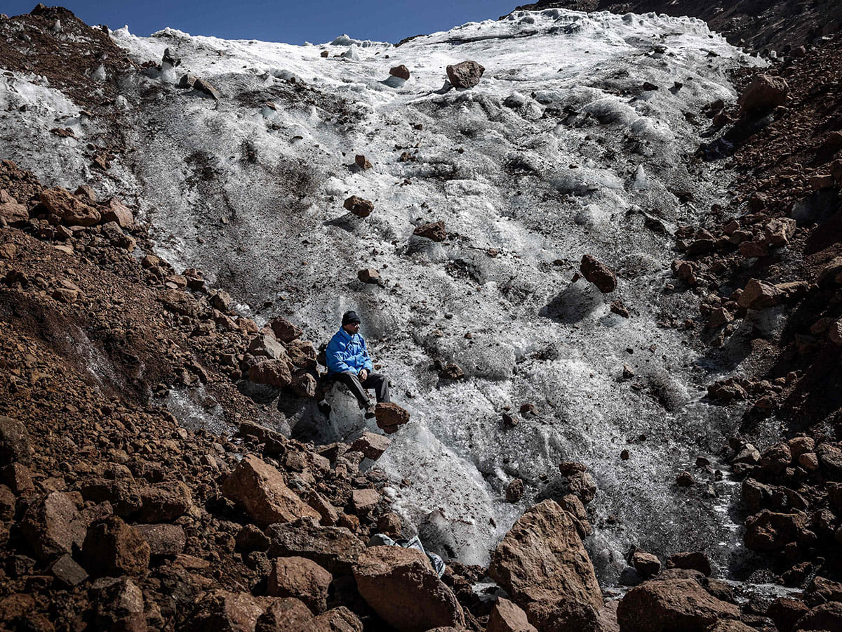 Professional mountaineer guide Charles Kibaki Muchiri, 50, observes the landscape while seated at the melting foot of Lewis Glacier near the summit of Mount Kenya