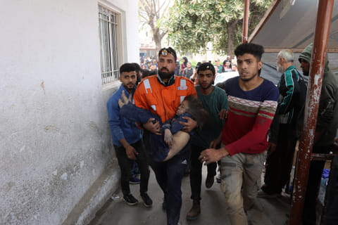 A Palestinian rescuer carries the body of a child killed in an Israeli strike on a residential area in Gaza City's Shujaiyya neighbourhood.