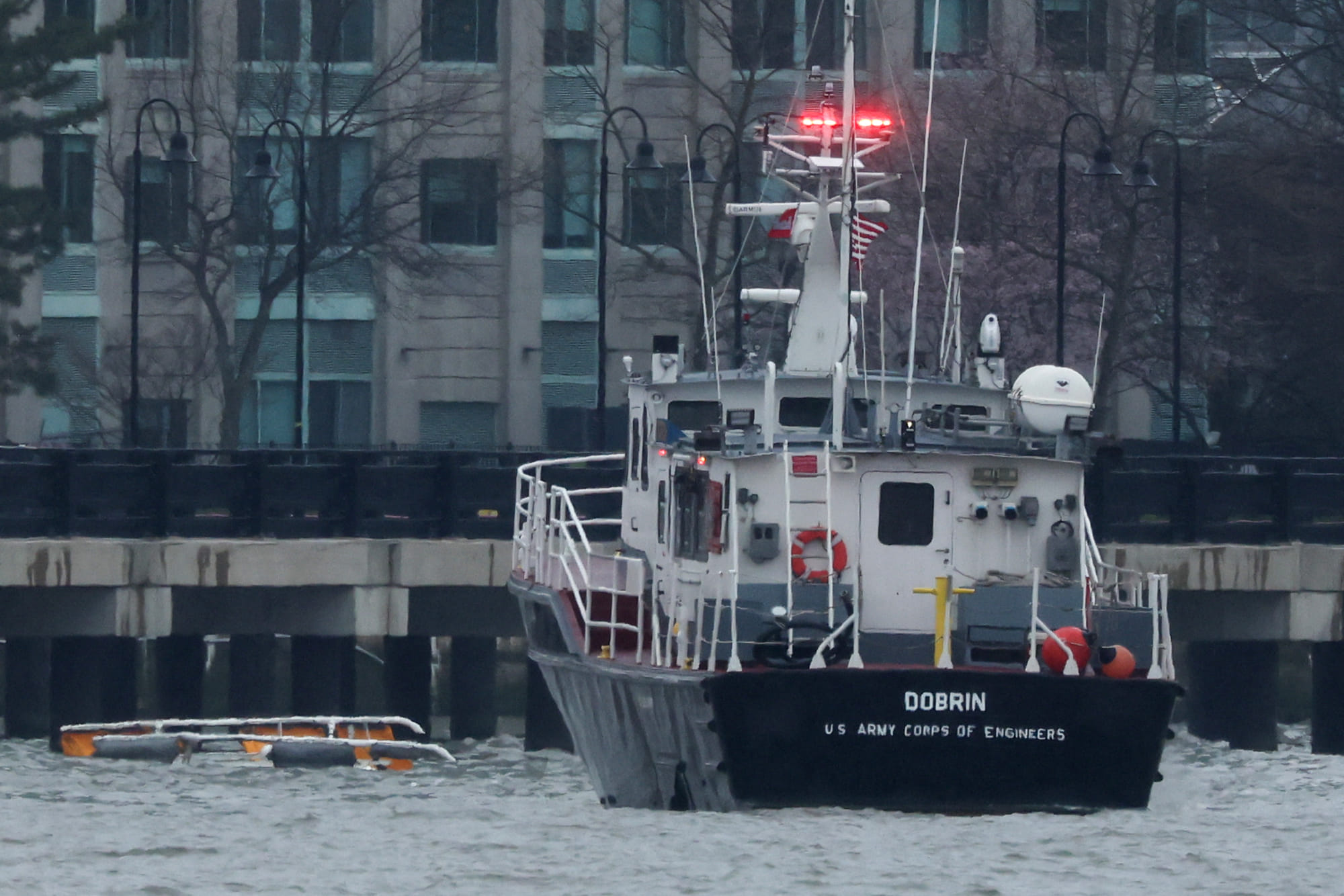 A helicopter's landing skids (L) are seen in the water next to a US Army Corps of Engineers boat off the shore of Hoboken, New Jersey, as seen from New York after it crashed into the Hudson River on April 10, 2025.