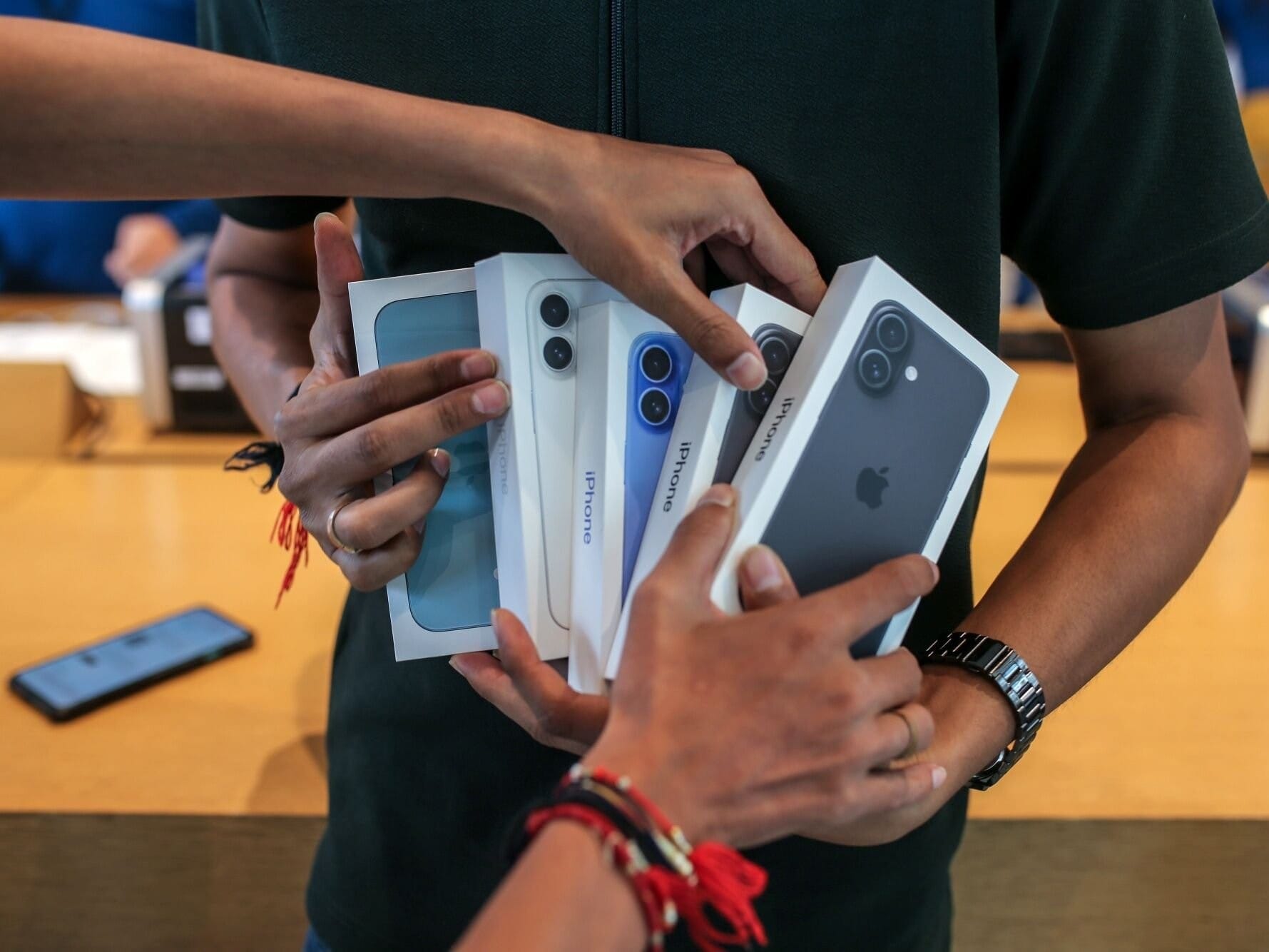 A man holds Apple iPhones at a shop in Mumbai, India.