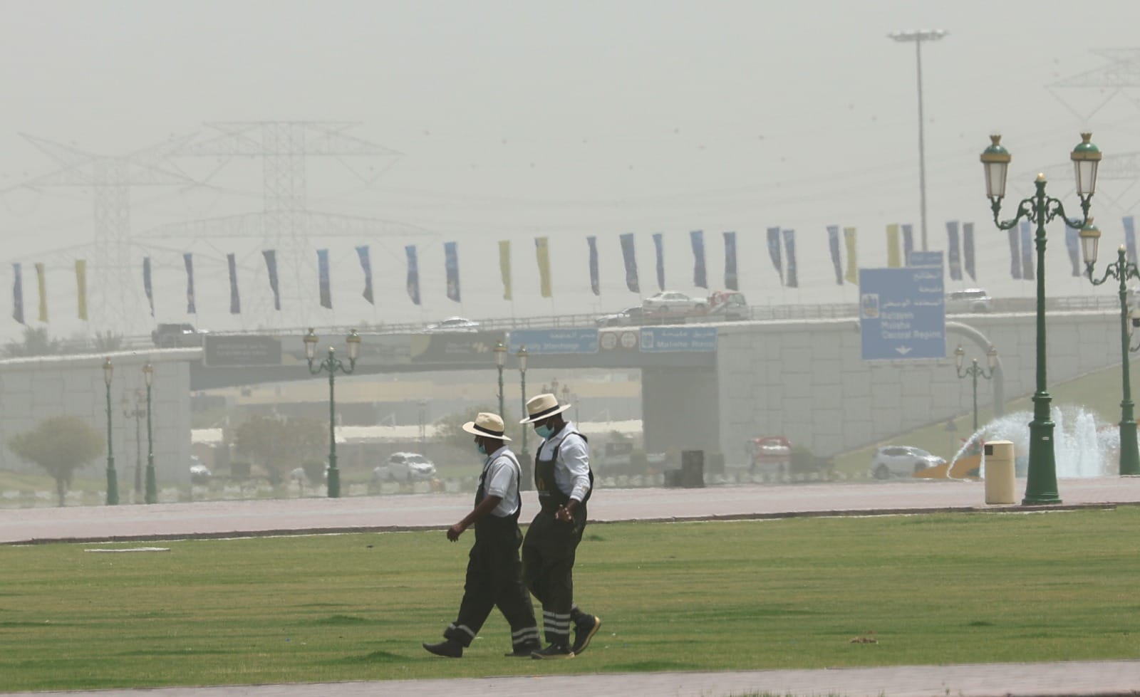 Workers wearing masks in dusty weather with low visibility in Sharjah.