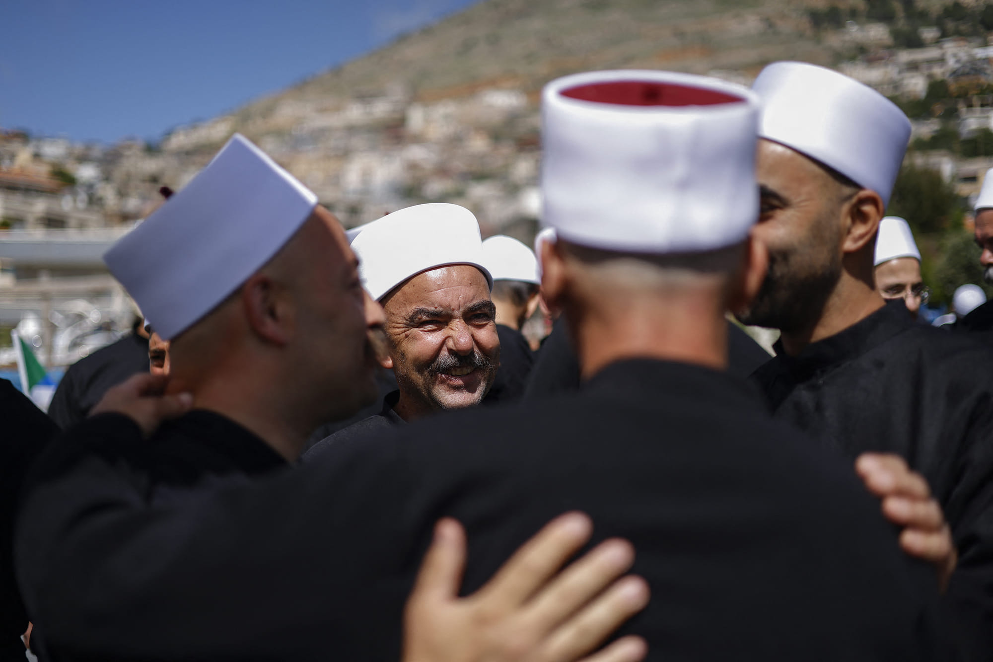 Druze clerics welcome visitng counterparts who just arrived from Syria in a bus through a border barrier guarded by Israeli soldiers, in the village of Majdal Shams in the Israeli-annexed Golan Heights, on April 25, 2025.