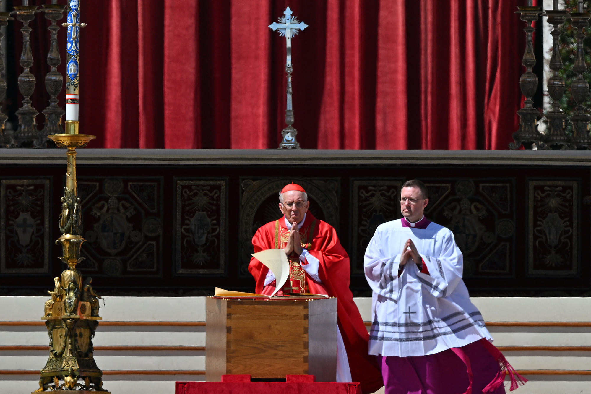 The wind flips the pages of the Book of Gospels as Italian cardinal Giovanni Battista Re (L) officiates near the coffin of late Pope Francis during the funeral ceremony at St Peter's Square in the Vatican, on April 26, 2025.