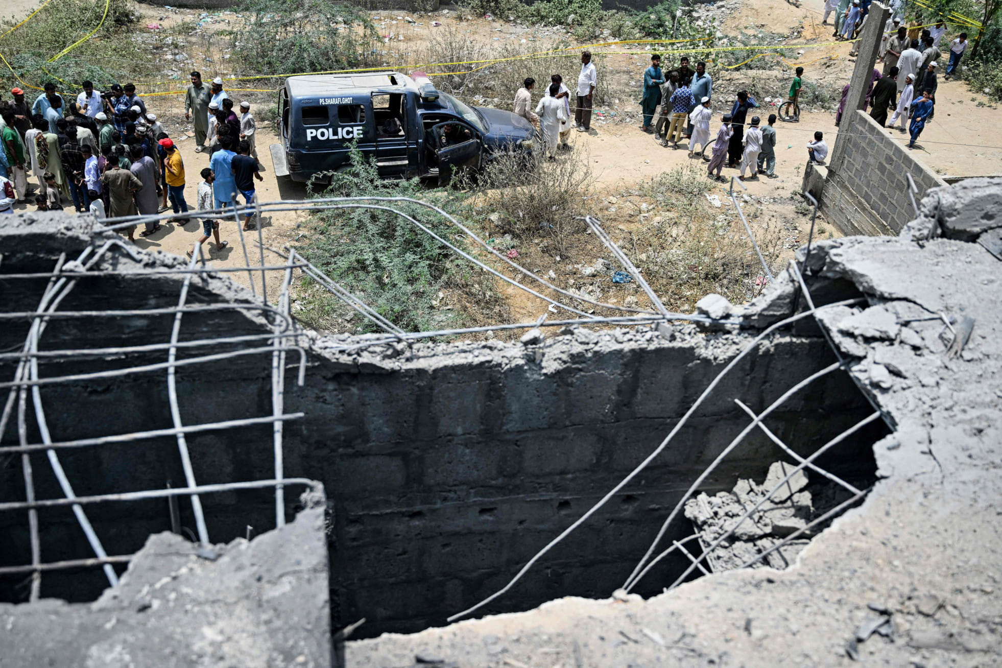 Residents gather as police personnel inspect the site where an alleged drone was shot down in Karachi on May 8, 2025. 