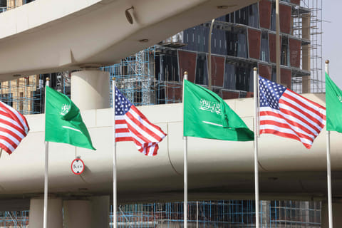 Saudi and US flags flutter in front of a building under construction on a main road in Riyadh on May 12, 2025, hours before of a visit by US President Donald Trump to the kingdom.  