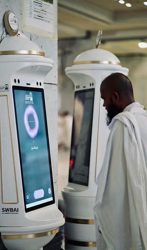 A Muslim worshipper seeks help from the Manara robot in the Grand Mosque in Mecca.  