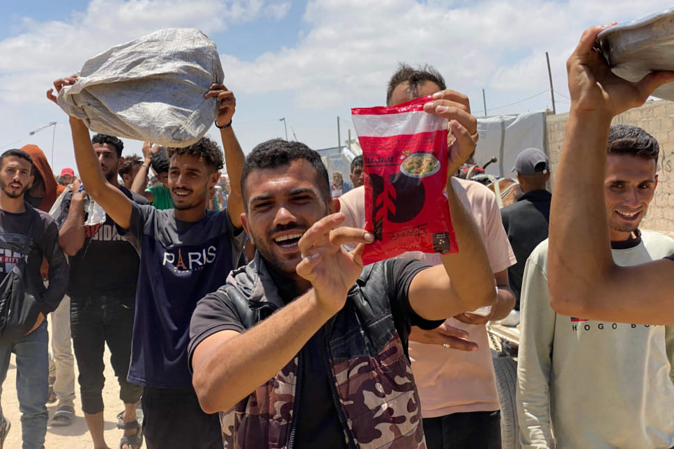 Displaced Palestinians react as they display items received from an aid distribution center in Khan Yunis in the southern Gaza Strip on May 28, 2025.  
