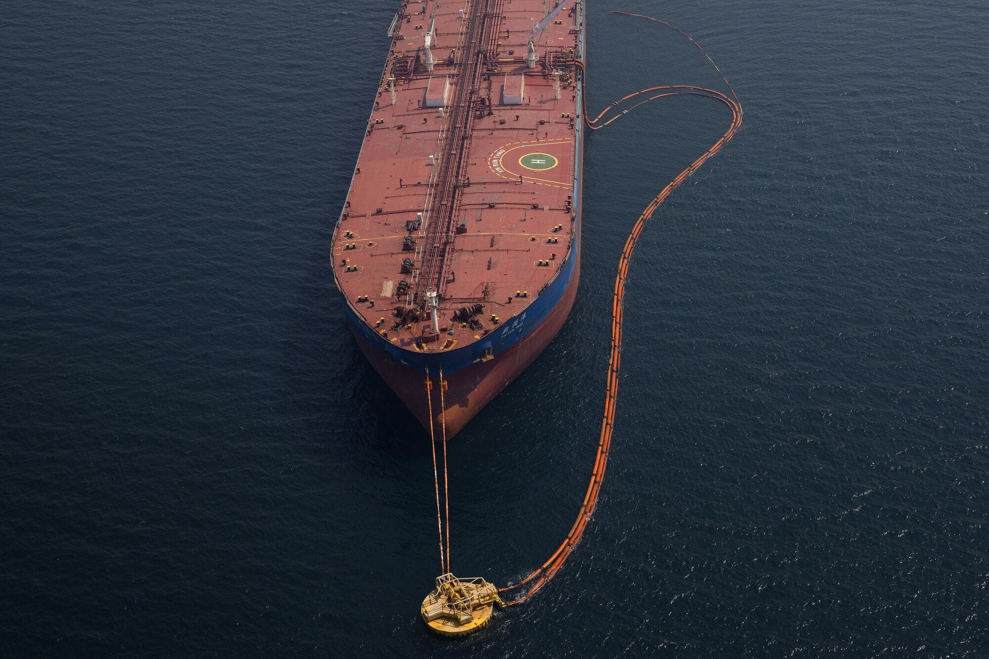 Pipes feed crude oil to a tanker.