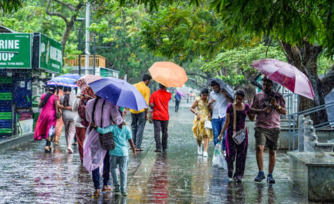 People walk through heavy rain at the Marine Drive walkway in Kochi, Kerala, India.