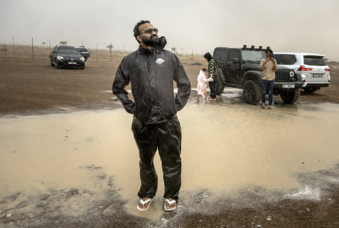 Mohammed Sajjad, known locally as "The Weatherman" (C) stands in the rain with others who took part in a "rain chase" in the emirate of Sharjah on June 7, 2025.