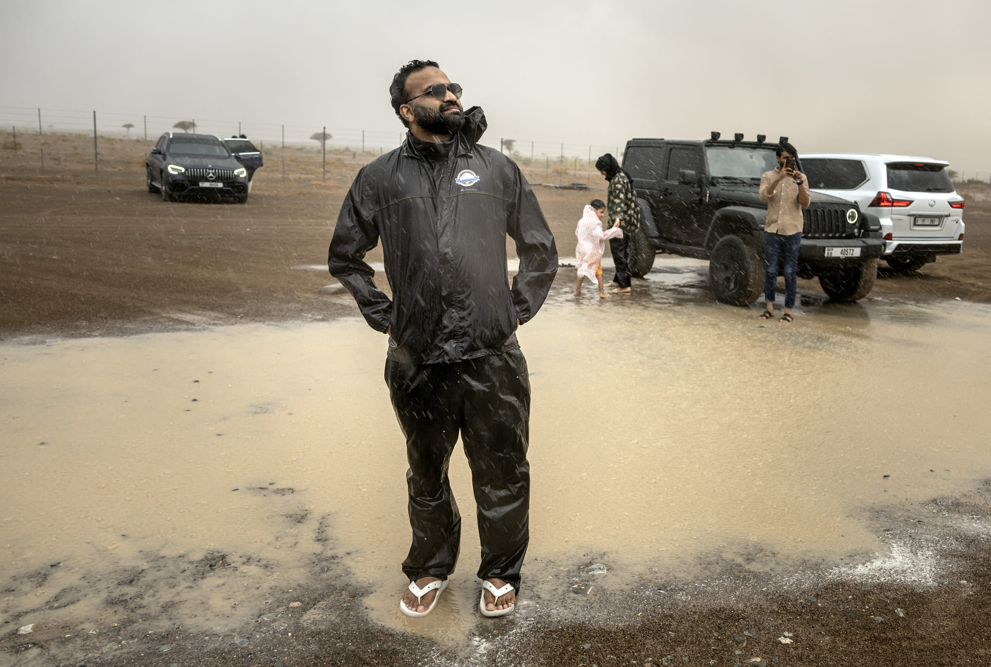 Mohammed Sajjad, known locally as "The Weatherman" (C) stands in the rain with others who took part in a "rain chase" in the emirate of Sharjah on June 7, 2025.