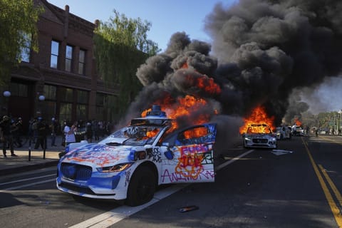Multiple Waymo taxis burn near the Metropolitan Detention Center of downtown Los Angeles following immigration raid protest.