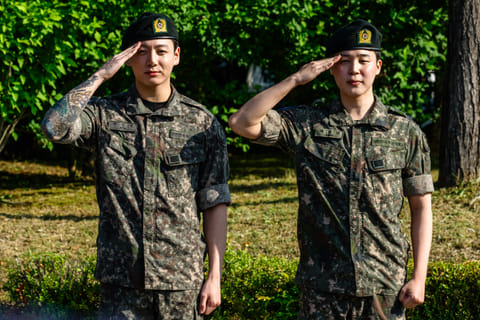 Jungkook and Jimin of K-pop supergroup BTS salute for the media and fans at an outdoor sporting facility in Yeoncheon on June 11, 2025, shortly after their release from 18 months of South Korean military service.
