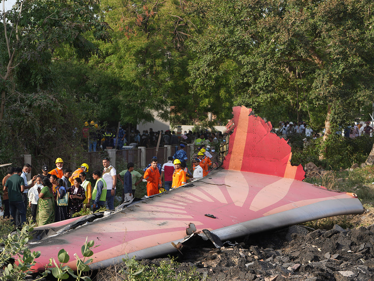 People stand around the debris of an airplane after it crashed in India's northwestern city of Ahmedabad in Gujarat state, on Thursday, June 12, 2025. 