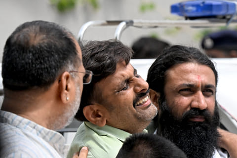 A family member (C) mourns the death of an Air India flight crash victim as he arrives to collect mortal remains outside a hospital mortuary in Ahmedabad on June 15, 2025.