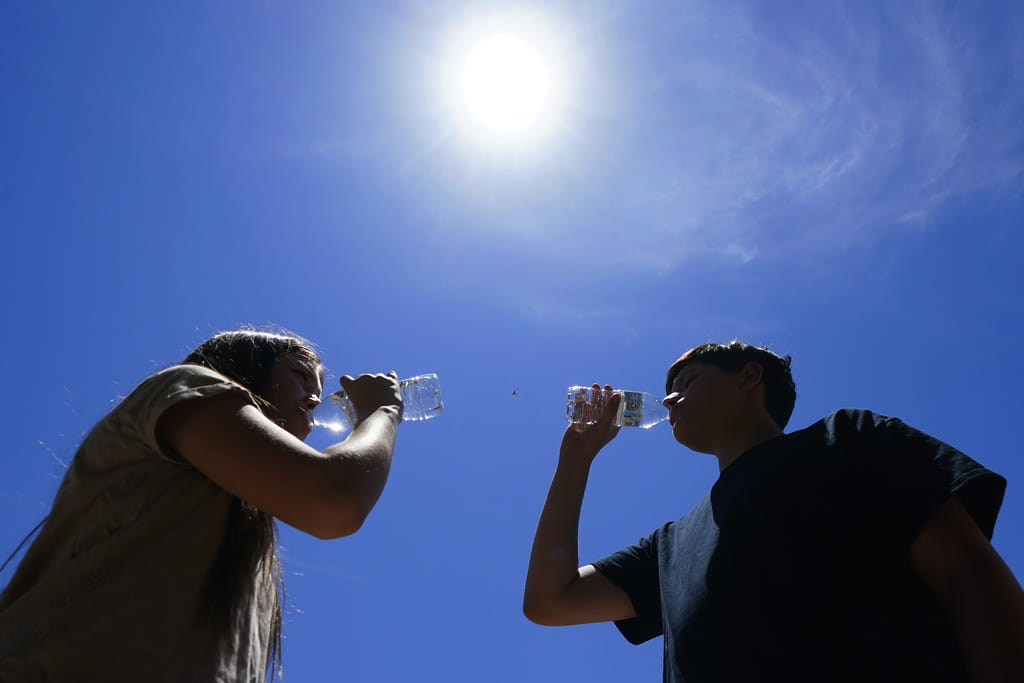 FILE - Tony Berastegui Jr., right, and his sister Giselle Berastegui drink water, July 17, 2023, in Phoenix.