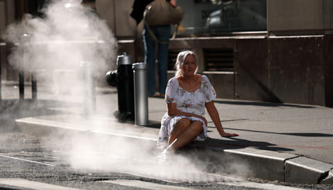 A tourist poses for pictures in steam grate on Wall Street June 23, 2025 as a excessive heat warning has been issued for NYC area.