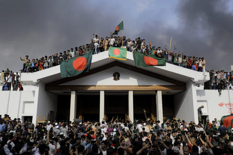 Anti-government protestors display Bangladesh's national flag as they storm Prime Minister Sheikh Hasina's palace in Dhaka on August 5, 2024.