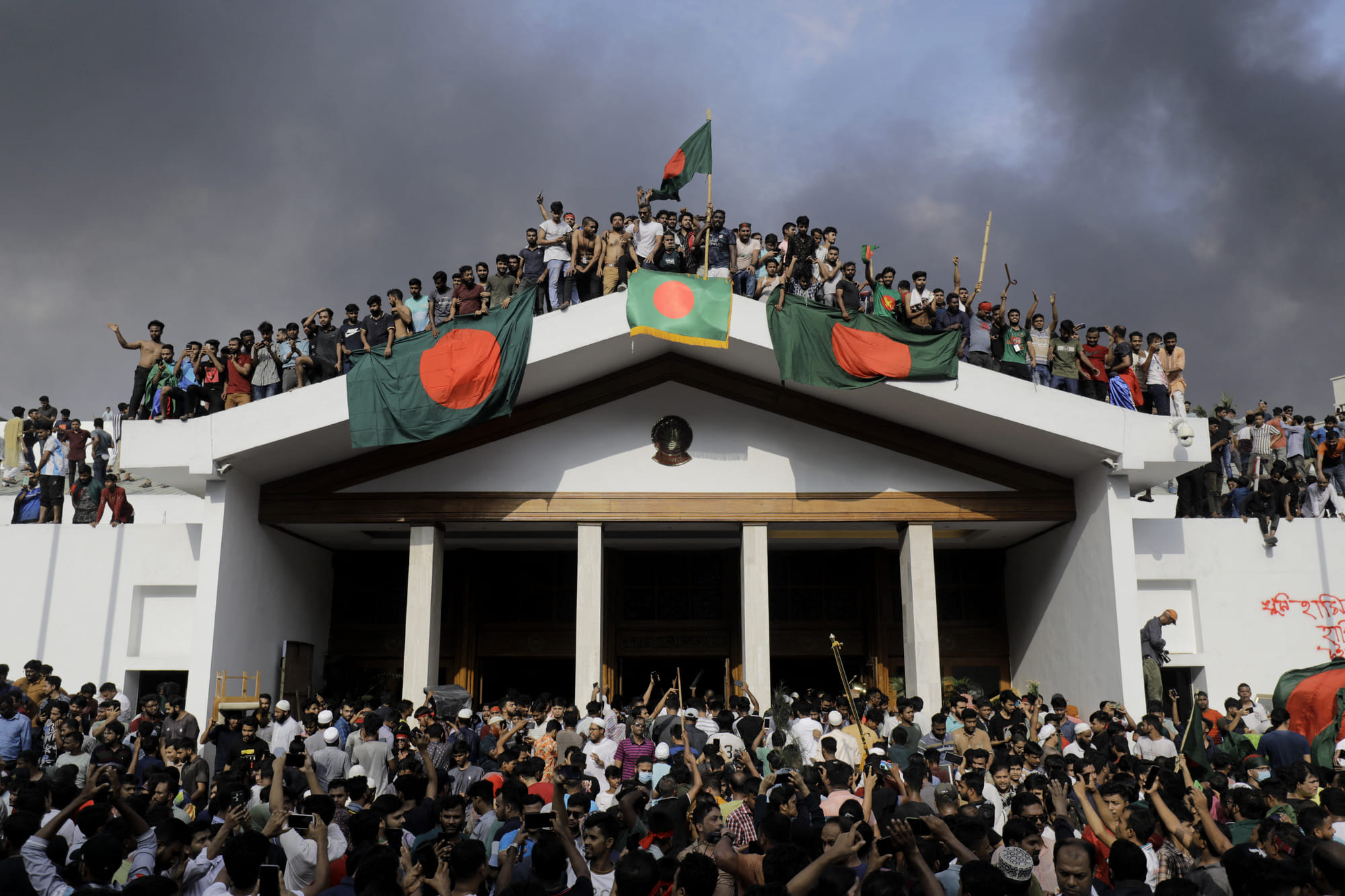 Anti-government protestors display Bangladesh's national flag as they storm Prime Minister Sheikh Hasina's palace in Dhaka on August 5, 2024.