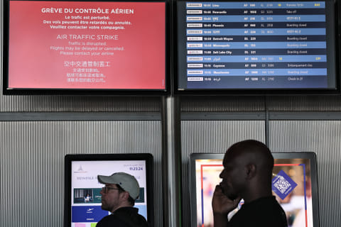 Passengers look at the departures information board at Roissy Charles-de-Gaulle airport, outside Paris
