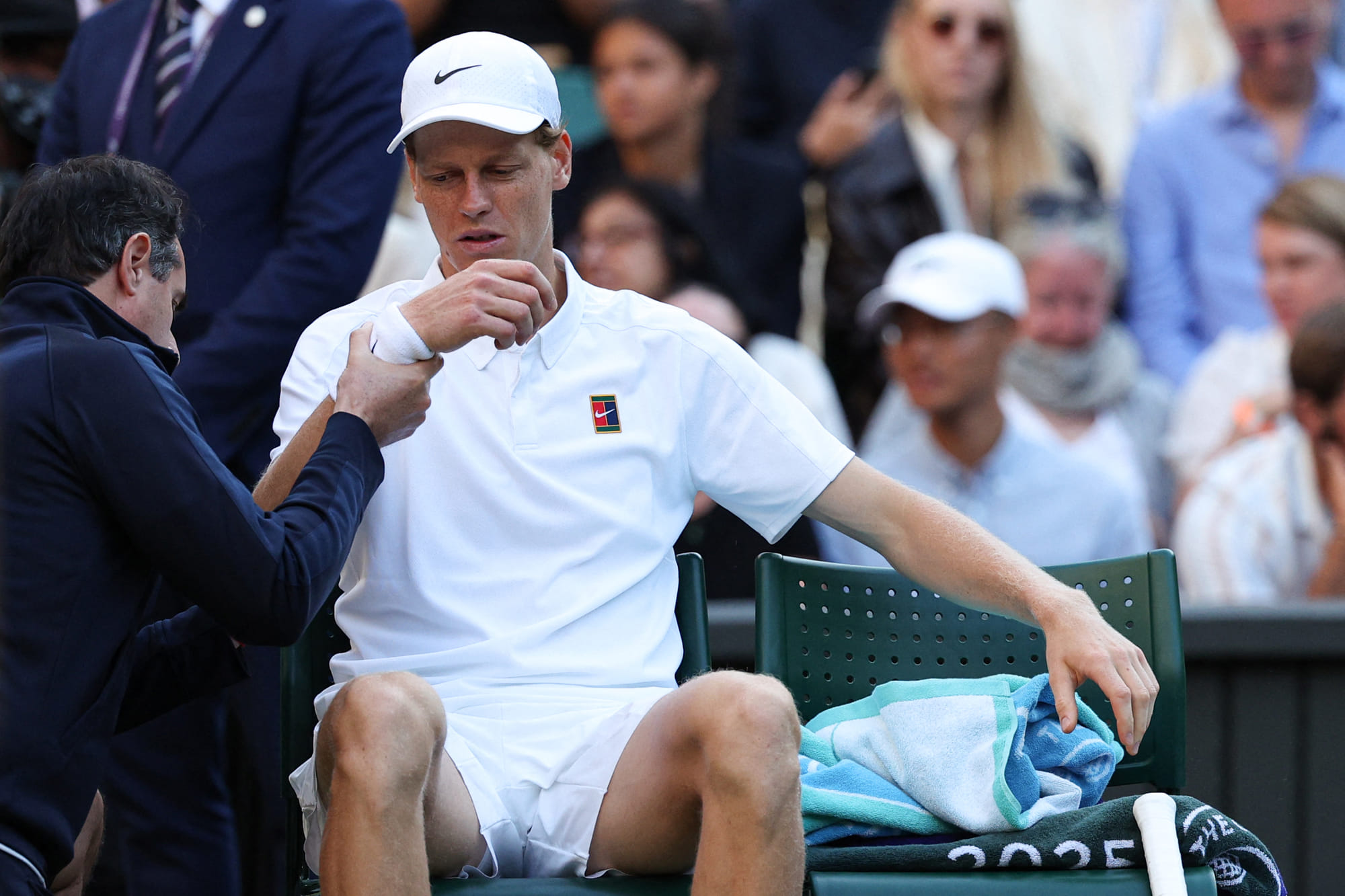 Italy's Jannik Sinner reacts as he receives medical treatment during his men's singles fourth round tennis match against Bulgaria's Grigor Dimitrov on the eighth day of the 2025 Wimbledon Championships at The All England Lawn Tennis and Croquet Club in Wimbledon, southwest London, on July 7, 2025.