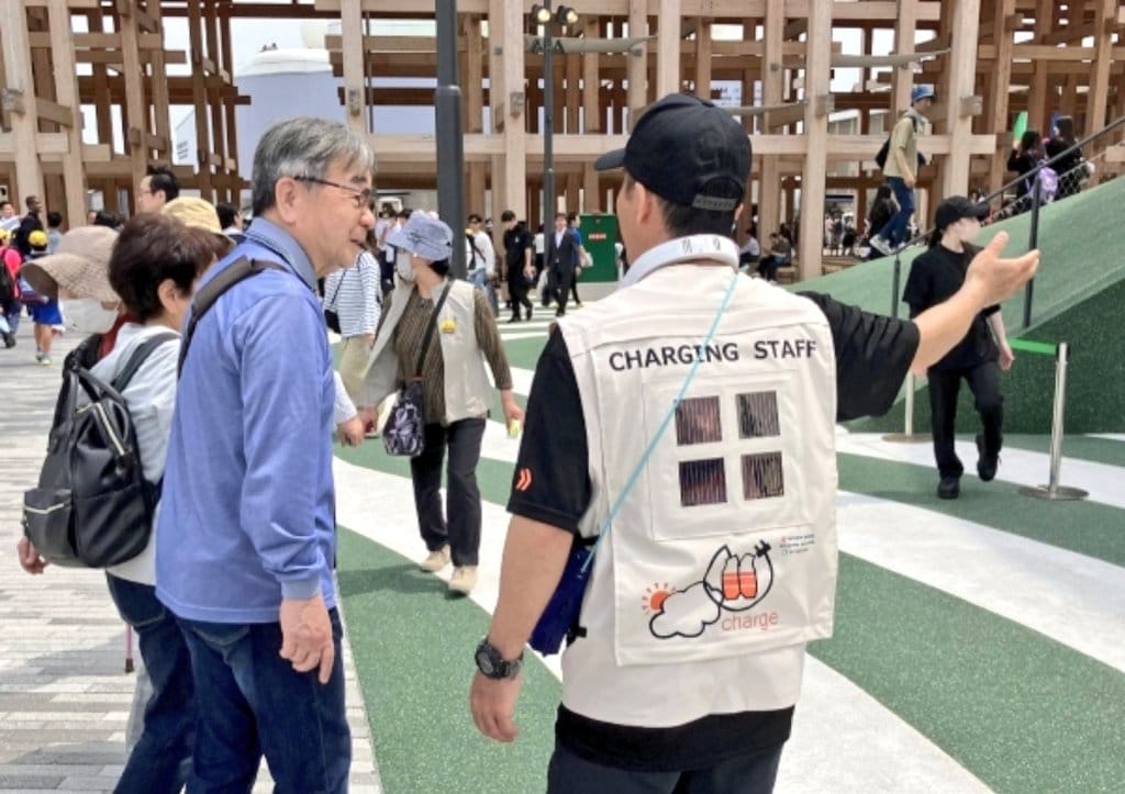 Harnessing the sun in style: On-site guides at Osaka Expo 2025 debut futuristic vests fitted with ultra-light perovskite solar cells—powering neck fans as they brave the summer heat.
