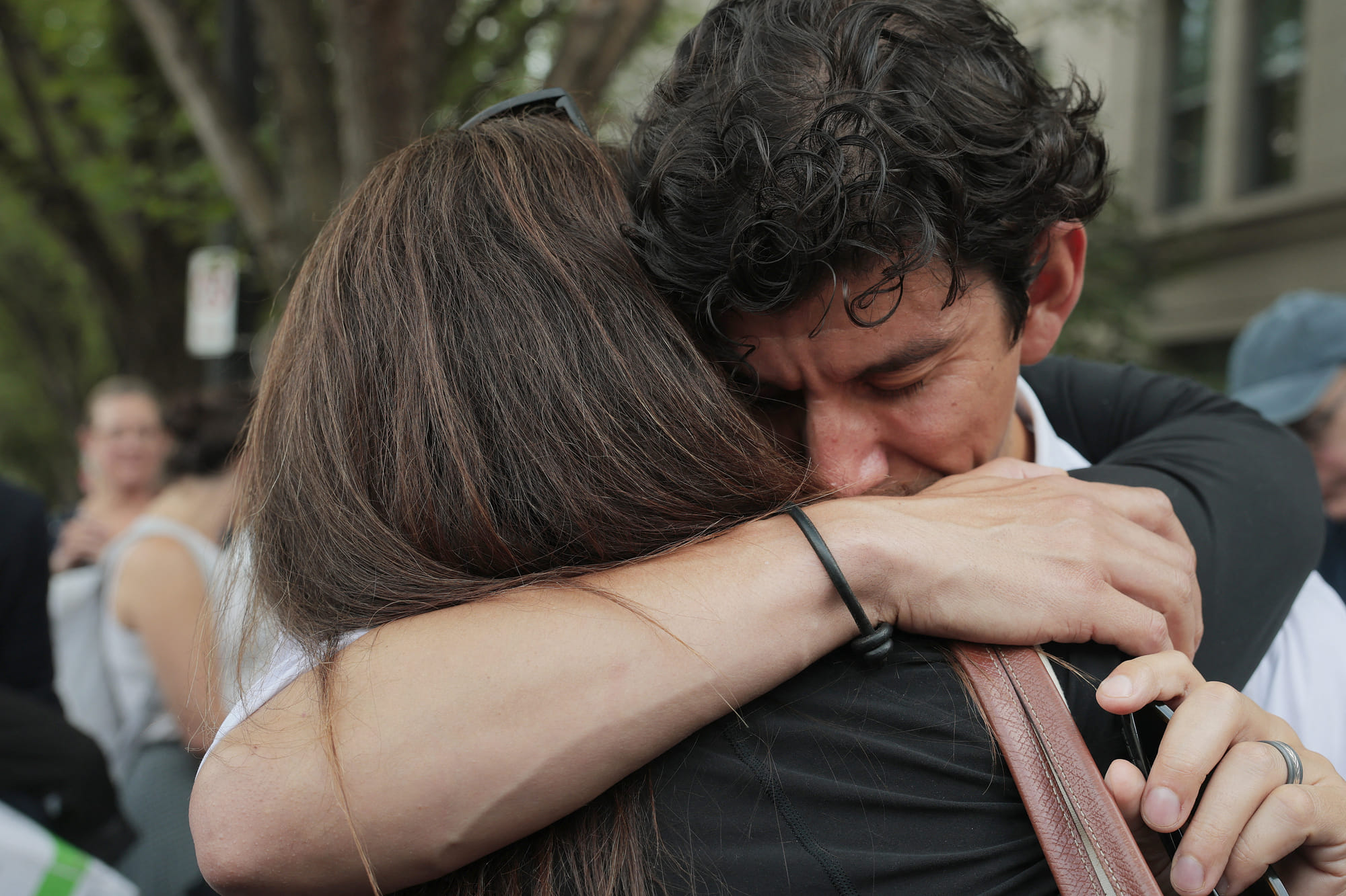 US State Department employee (L) who was recently laid off is hugged at a rally in support federal workers near the Harry S. Truman Federal Building on July 11, 2025 in Washington, DC. x