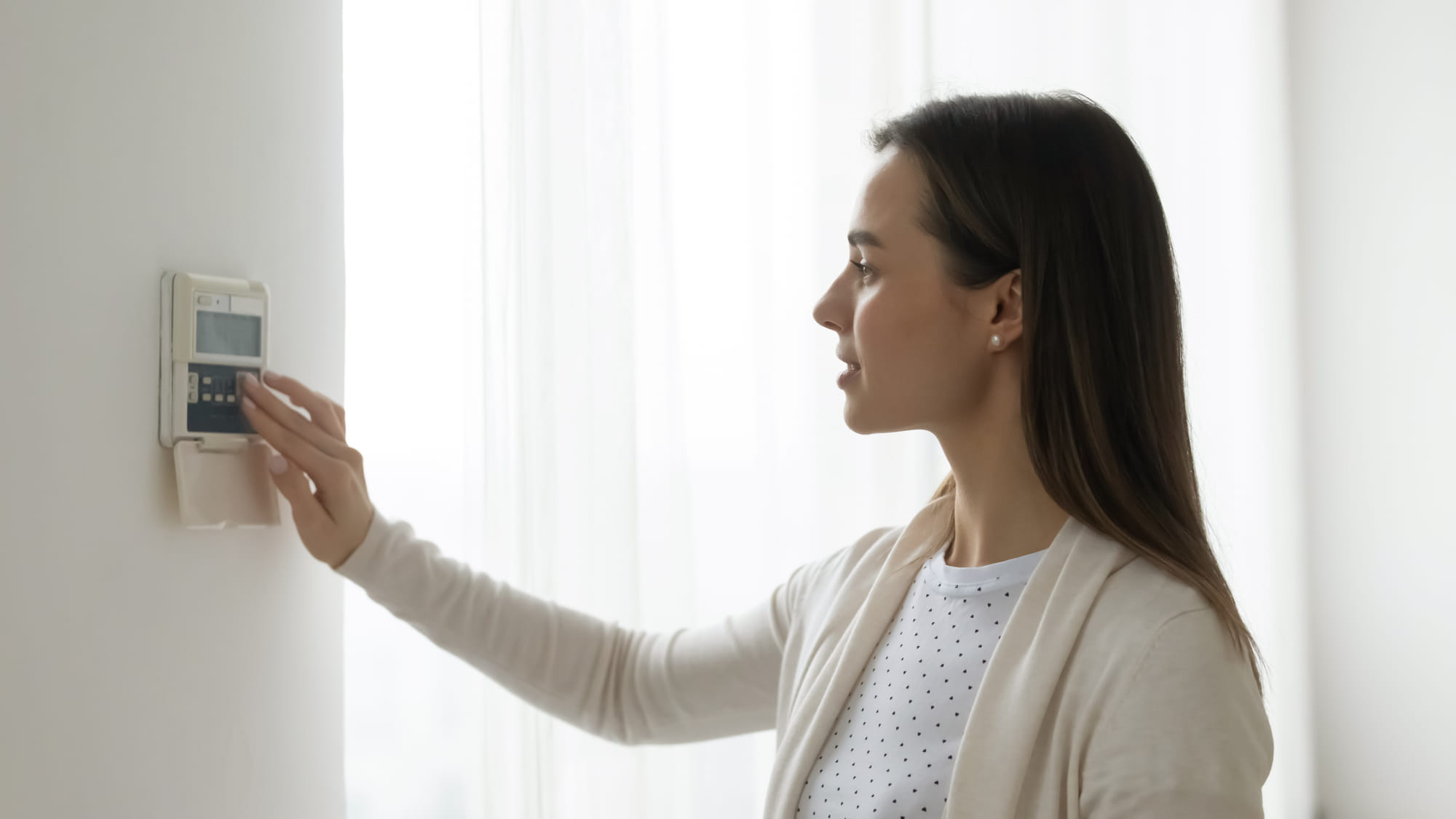 Young woman controlling air conditioning unit