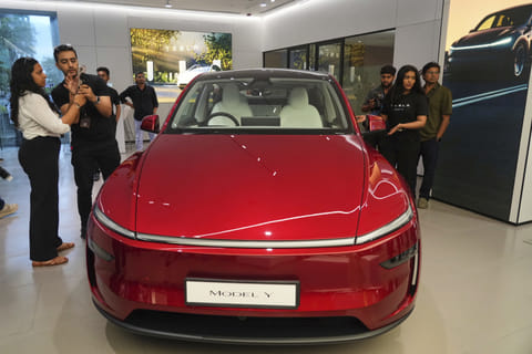 Media personnel gather near the Tesla's 'Model Y' vehicle during the inauguration of India's first Tesla showroom, in Mumbai on July 15, 2025.