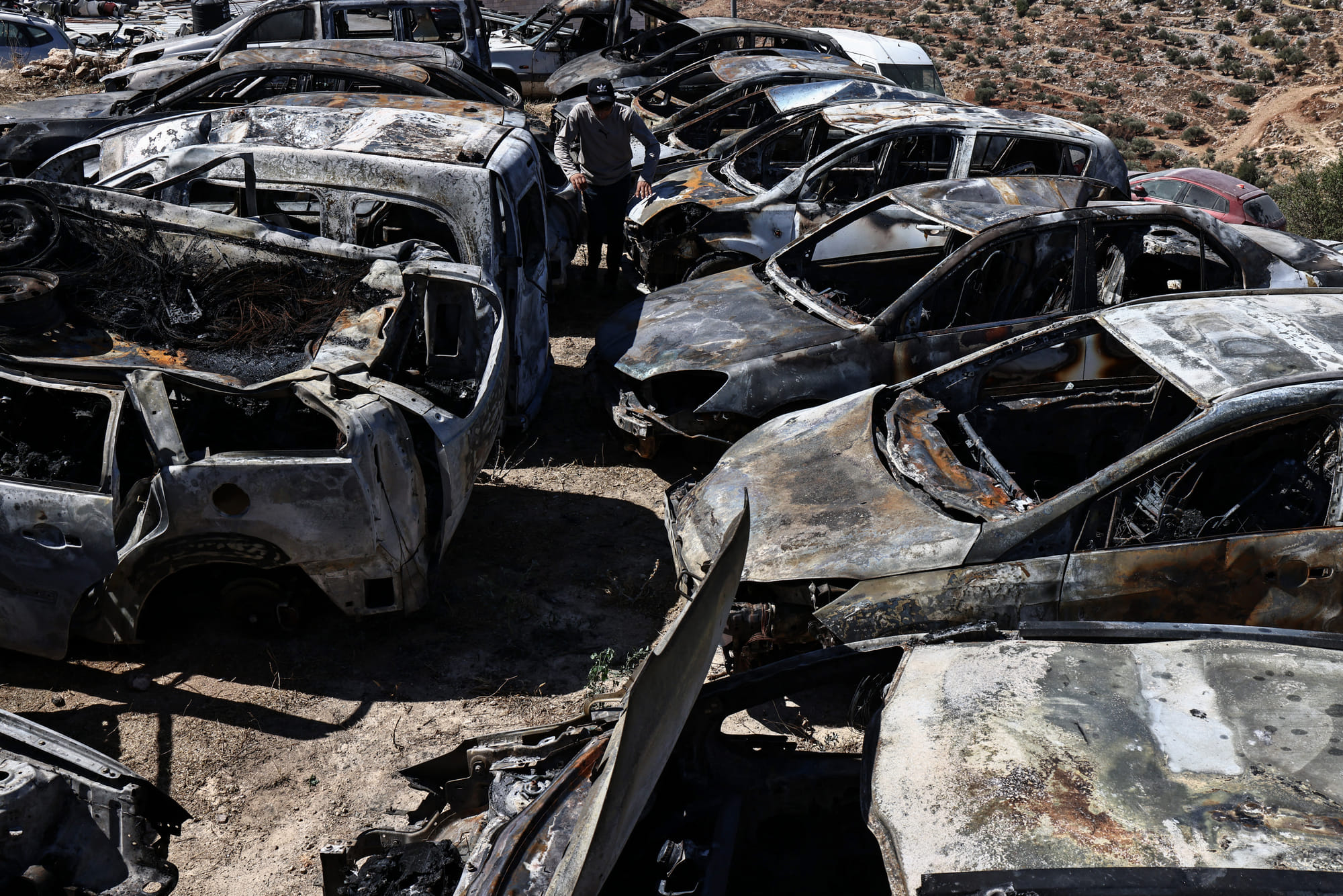A Palestinian man walks amid destroyed cars that were set alight during a reported late-night attack by Israeli settlers on the village of Burqa, east of Ramallah in the Israeli-occupied West Bank on July 15, 2025.